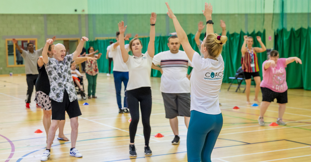 Inclusive group exercise session led by a Sport for Confidence coach in a sports hall