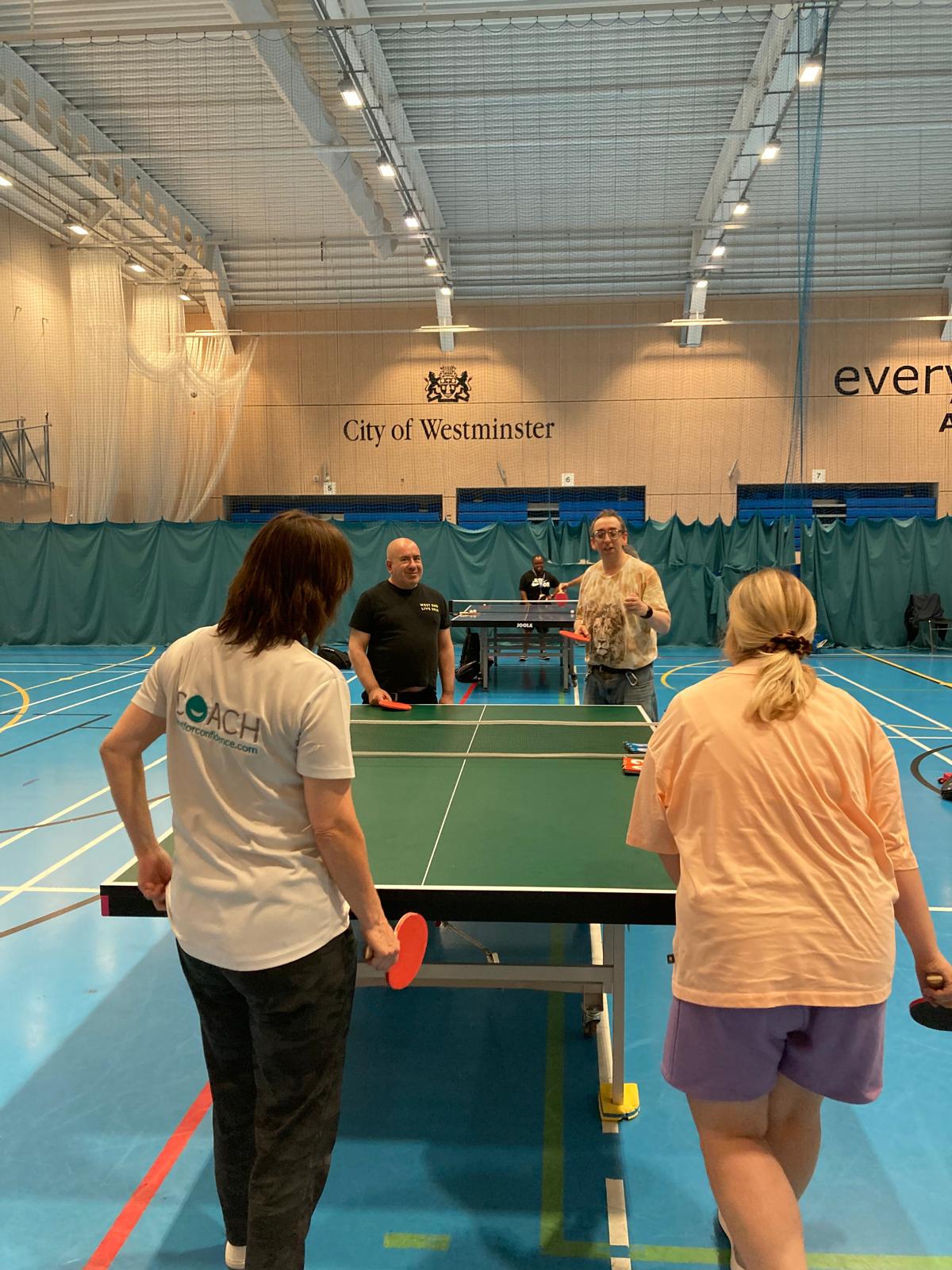 Participants taking part in a table tennis session at an indoor sports centre