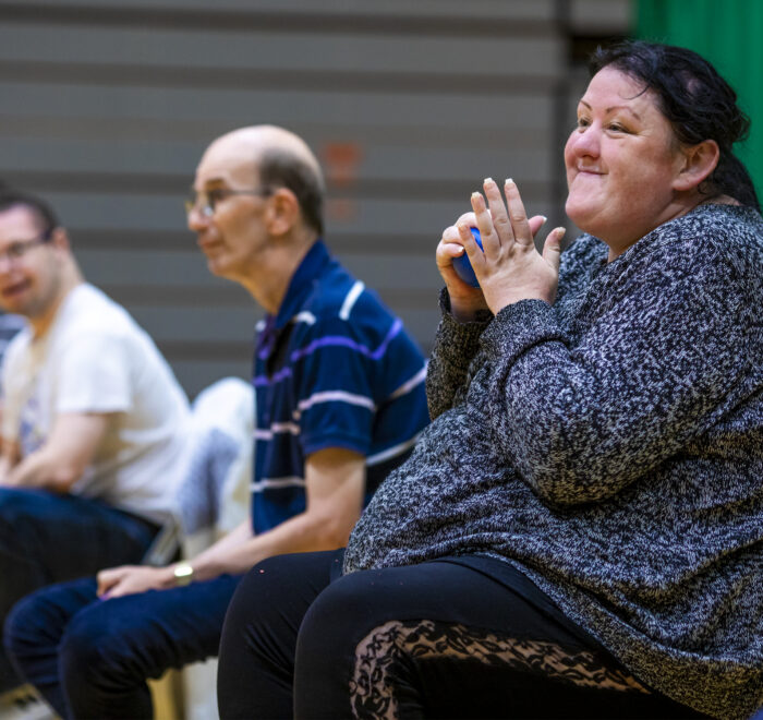 Community-Impact Smiling woman clapping taking part in a group sports activity