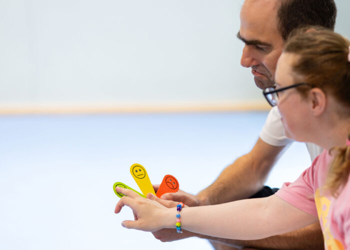 Coach supporting a participant during an inclusive wellbeing activity using emotion and communication tools