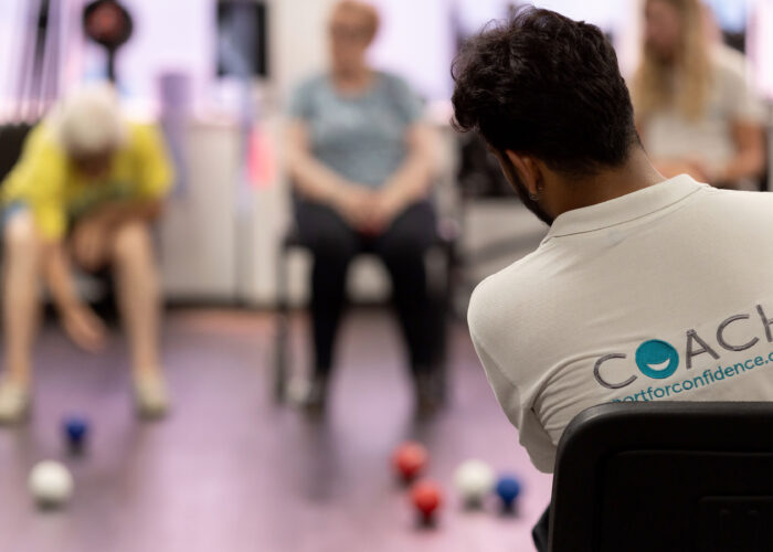 Coach supporting participants during an inclusive seated activity session with Sport for Confidence