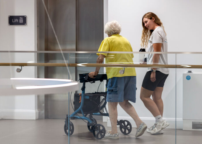 Woman using a walking frame talking to a member of Sport for Confidence staff