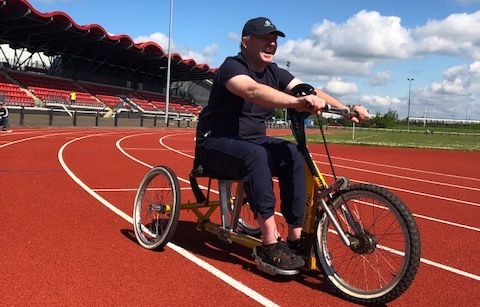 Man using an adapted tricycle on an athletics track