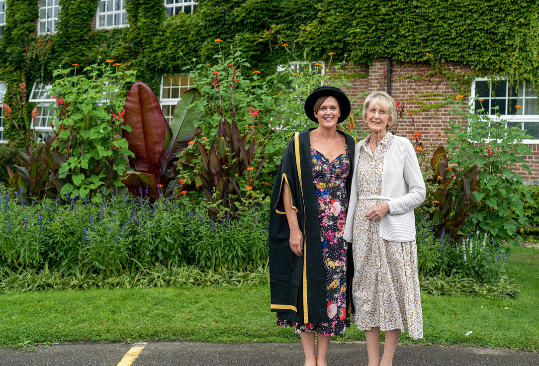 Lyndsey Barrett and guest standing in a garden at graduation ceremony