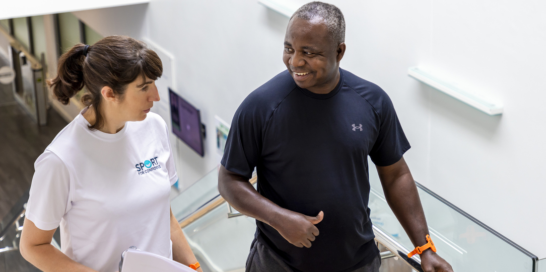 Sport for Confidence staff member walking and talking with a participant in a fitness setting