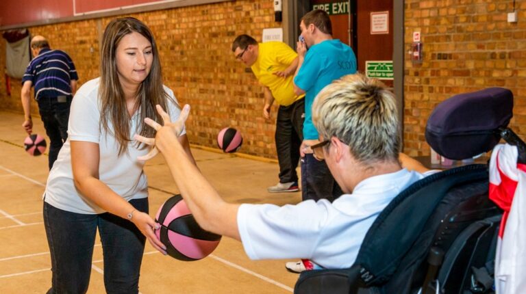 Coach supporting participant during accessible basketball session