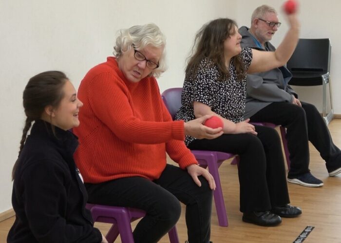 760-0-0-0-10000-10000-1084 Participants taking part in a seated ball activity during an inclusive community exercise session