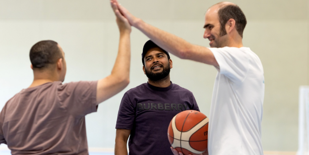 Participants celebrating with a high five during an indoor basketball session