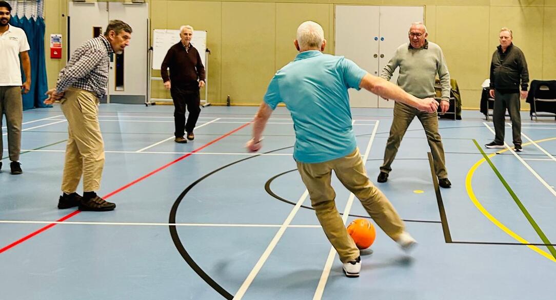 Older adults taking part in an indoor football activity session