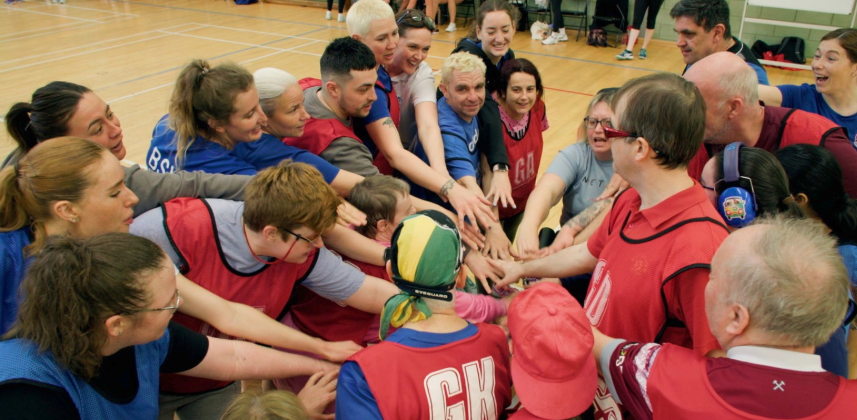 Participants gathered in a team huddle during an inclusive sports session