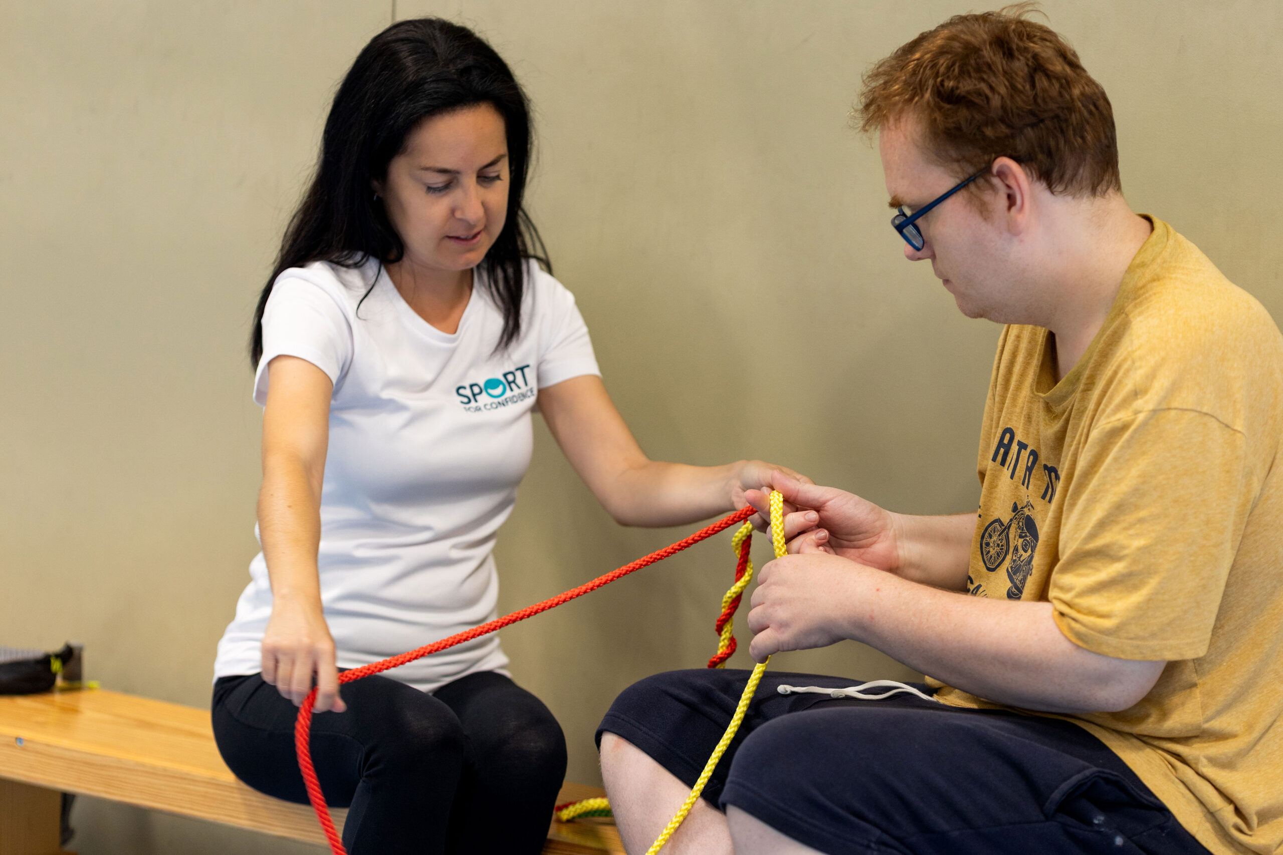 Woman and man sitting on a bench tying ropes