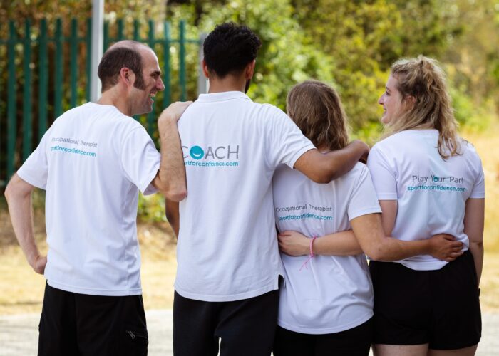 Join our Team – Supportive Team Four Sport for Confidence team members standing outdoors with their arms around each other, smiling and wearing branded staff shirts.