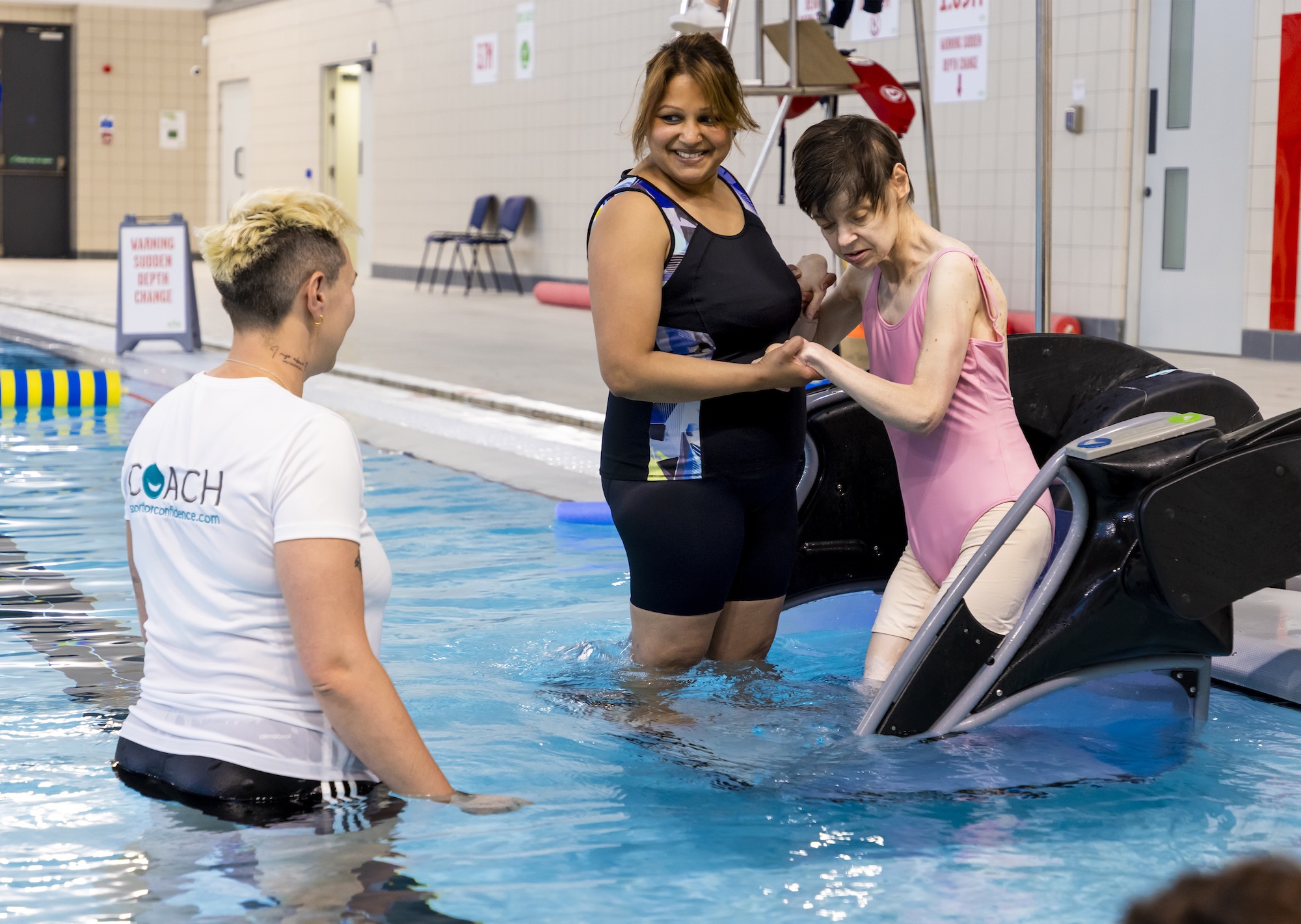 Sports coach helping people into a swimming people